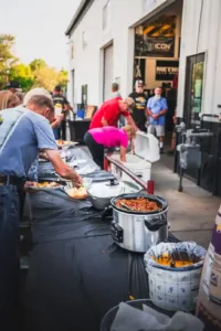 Buffet table with crockpots and guests serving food at Summit 4X4 community event