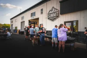 Community members lined up at tables outside Summit 4X4 shop with logo sign on building.