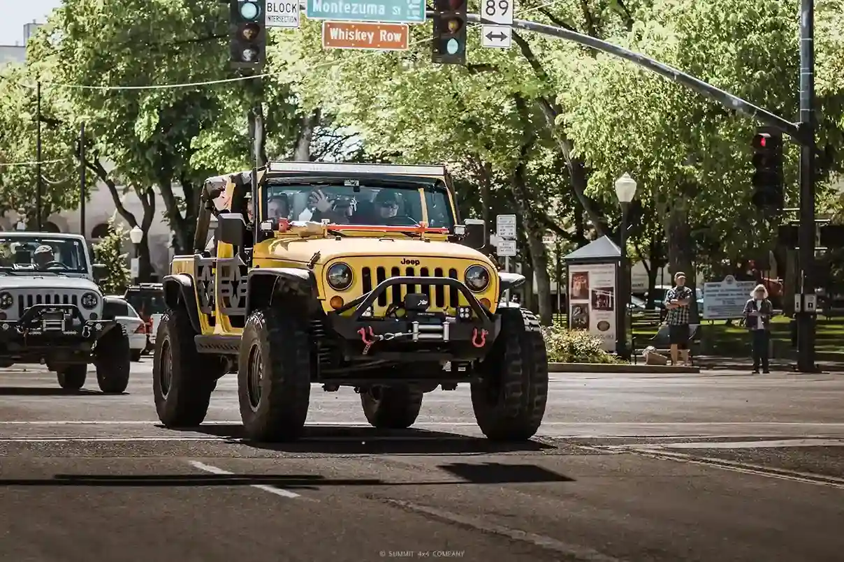 Yellow Jeep Wrangler with off-road upgrades driving through downtown Prescott during a Summit 4X4 event